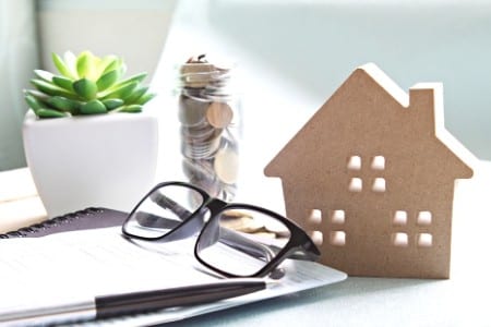 Jar of coins next to plant and model of house