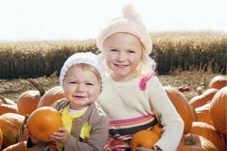 sisters sitting on pumpkins