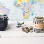 Map with camera, jar of travel money, sunglasses and straw hat