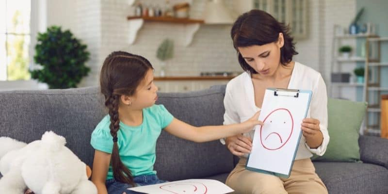 child pointing at drawing of sad face