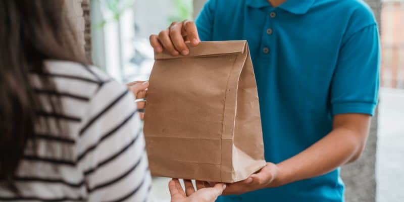 Handing over paper bag of food delivery