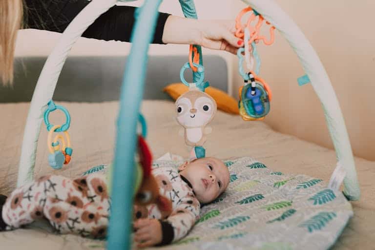 Cute baby on playmat with colorful hanging toys. Perfect for infant playtime theme.