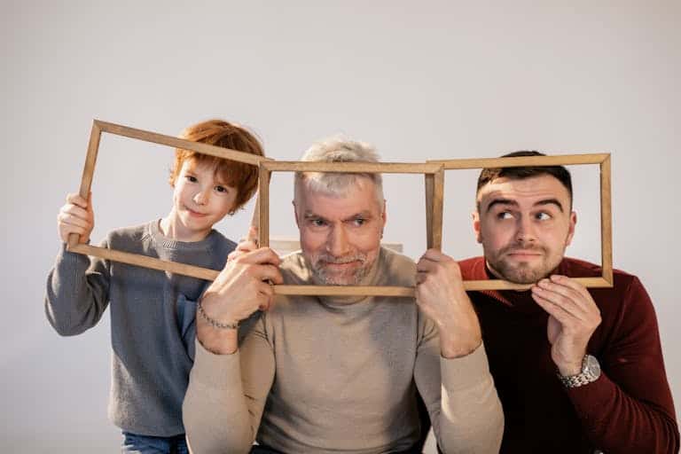 Warm studio portrait capturing a playful moment among three generations with wooden frames.